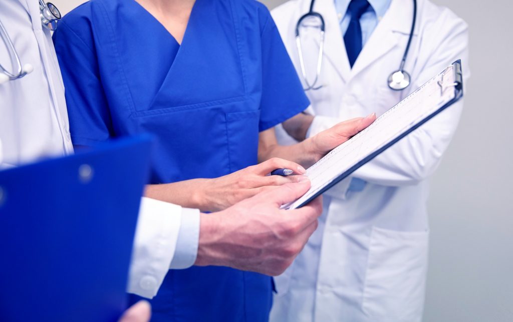 close up of doctors with clipboard at hospital